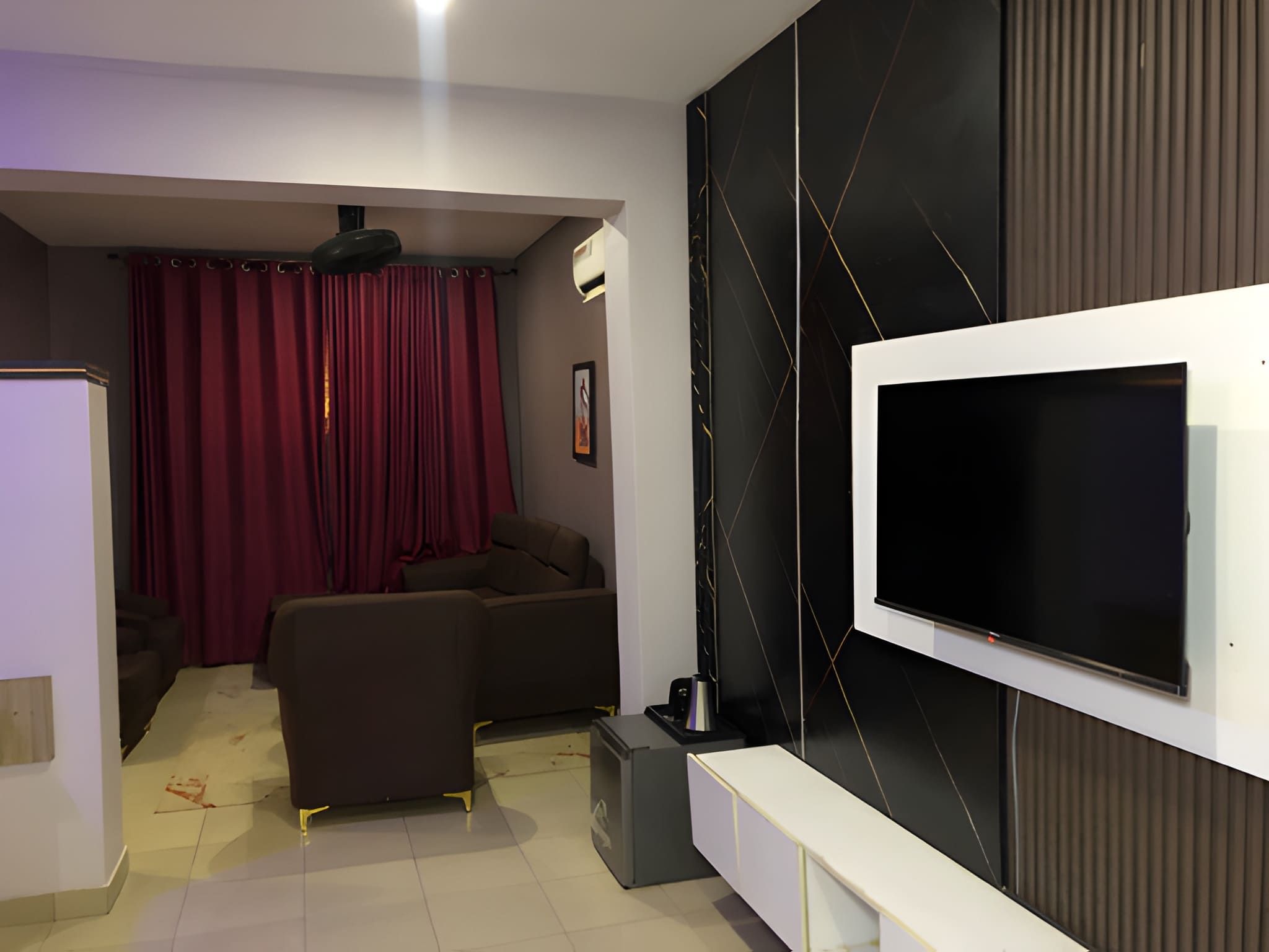 A modern living room with a flat-screen TV mounted on the wall, a sofa, a coffee table, and a small cabinet.