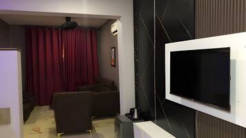 A modern living room with a flat-screen TV mounted on the wall, a sofa, a coffee table, and a small cabinet.