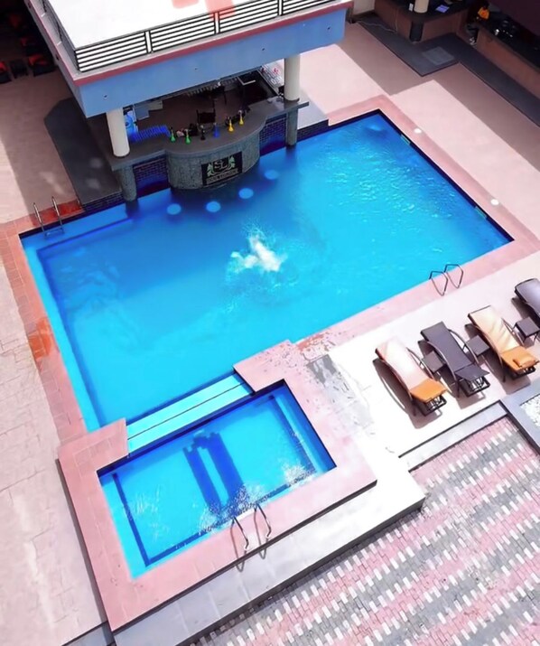 A swimming pool with a bar area and lounge chairs. - Soul Lounge Resort (Abuja)