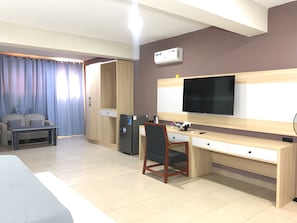 A hotel room with a bed, a desk, a chair, a television, and a minibar. - Soul Lounge Resort (Abuja)