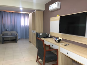 A hotel room with a bed, a desk with a chair, a TV, and an air conditioning unit. - Soul Lounge Resort (Abuja)