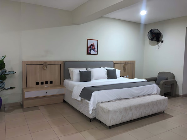 A modern bedroom with a bed, bedside tables, a chair, and a fan.