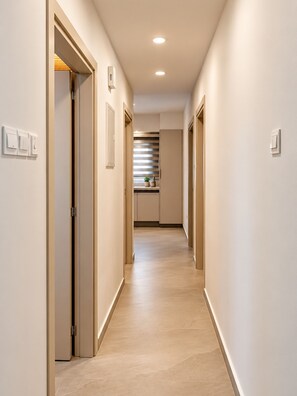 A hallway with doors, light switches, and a ceiling light. - River Plaza Apartment (Limassol)