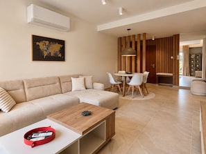 A modern living room with a sectional sofa, a dining table with chairs, and a coffee table. - River Plaza Apartment (Limassol)