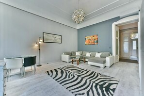 A modern living room with a sofa, coffee table, and a zebra-patterned rug. -  King of Church Budapest- Church-View Balcony Apartment  in Central Budapest (Budapest)