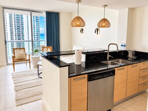 Una cocina moderna con lavavajillas, un fregadero y una zona de comedor con una silla y una mesa.