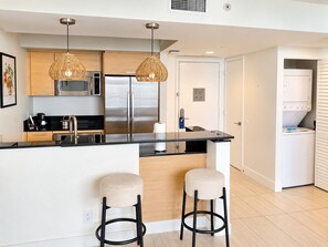 A modern kitchen with stainless steel appliances, a central island with stools, and pendant lighting. - 24th Floor 1-bedroom Full Kitchen Washer/Dryer Sunny Isles Direct Beach Access (Sunny Isles Beach)