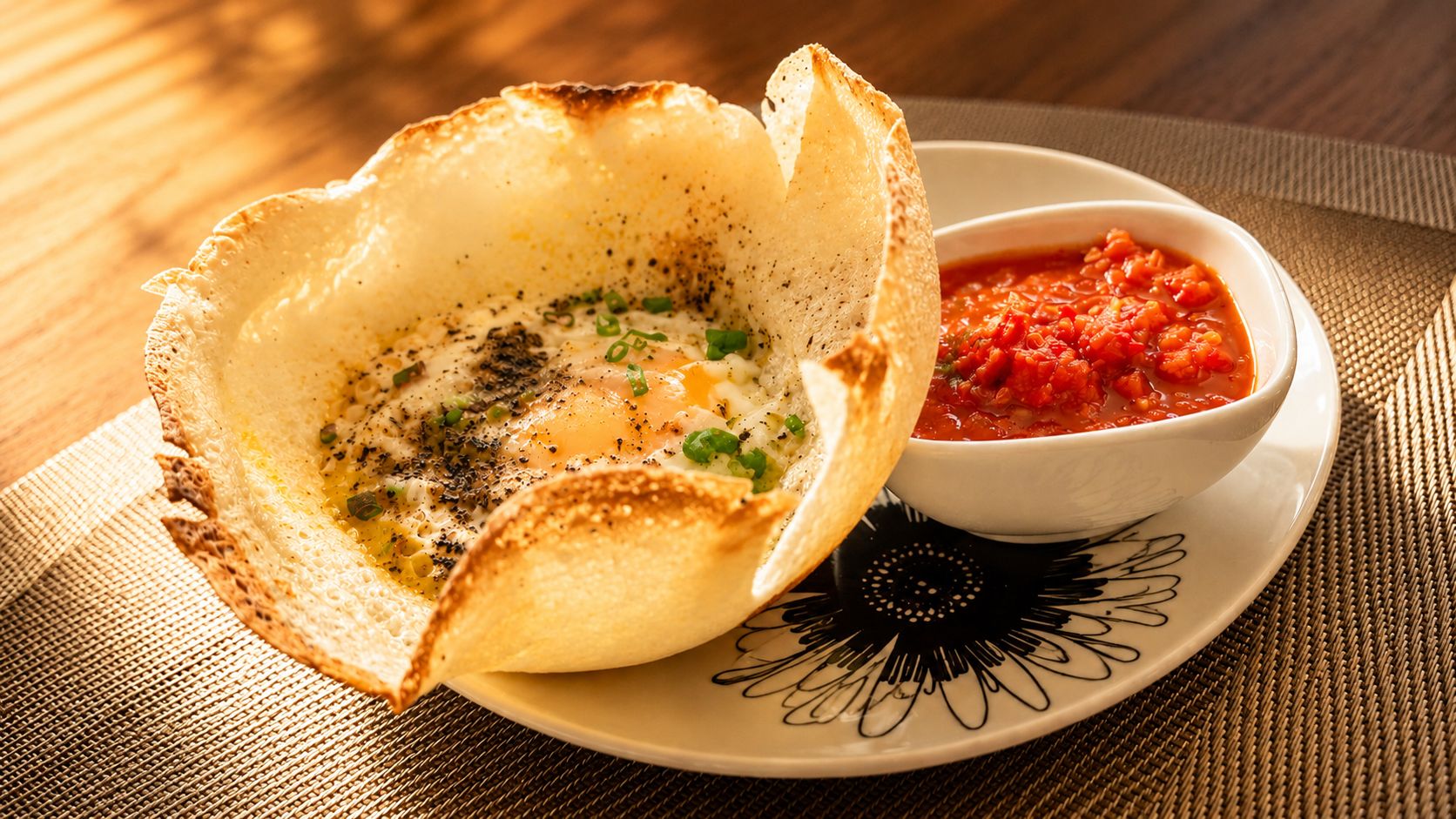 Un piatto con un bordo croccante, una ciotola di salsa rossa e un piatto decorato.