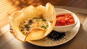 Un plato con un borde crujiente, una cazuela de salsa roja y un plato con diseño.