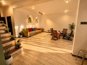 A spacious living area with a sofa, chairs, and a staircase with potted plants. - Claython Hills Ella (Ella)