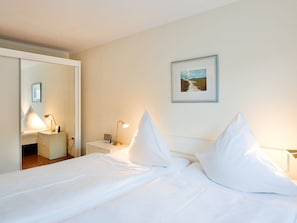 Ein Hotelzimmer mit Bett, Nachttischen, Spiegel und einem gerahmten Bild an der Wand.