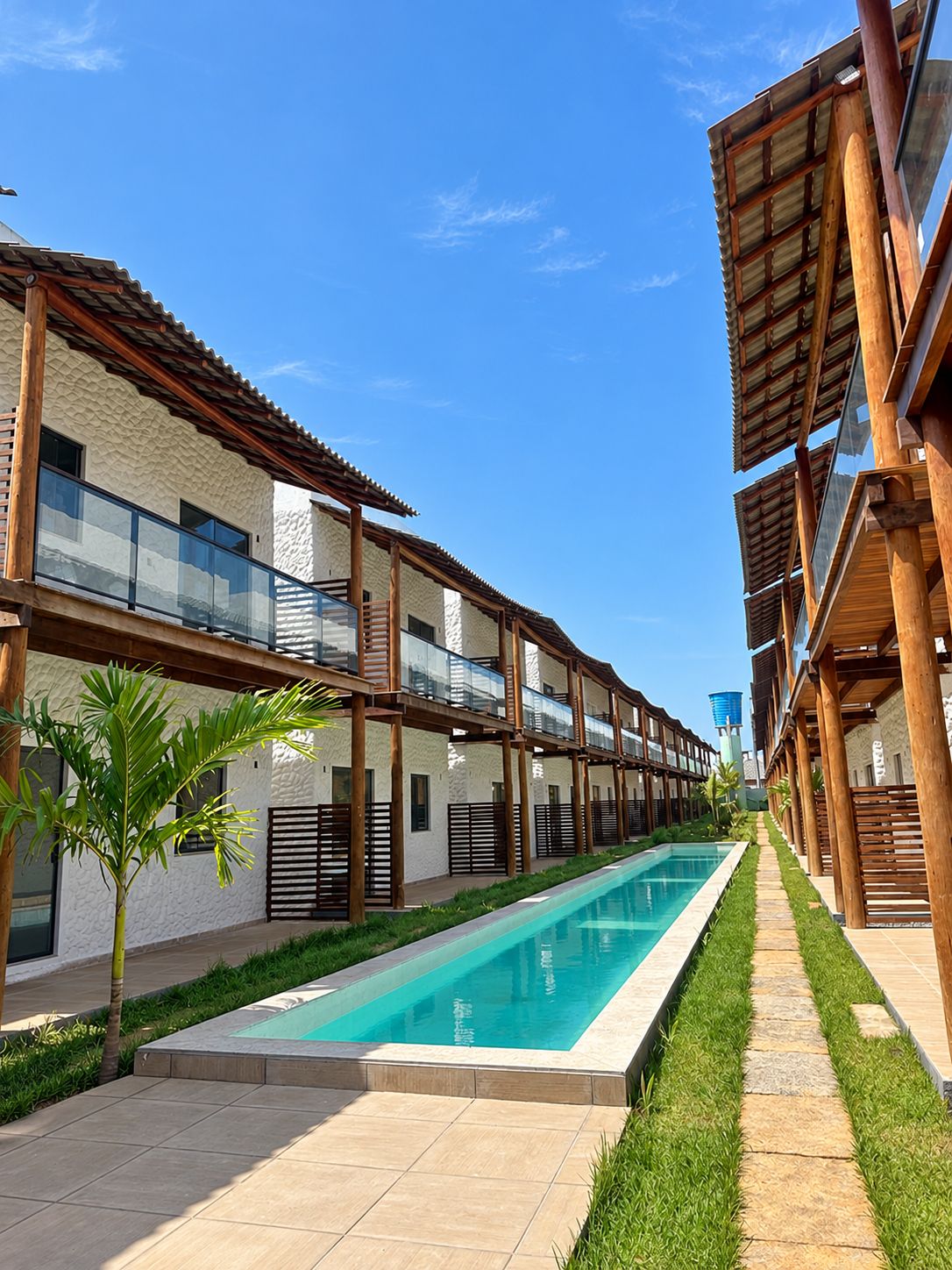 Ein modernes Hotel mit Schwimmbad, Holzbalkonen und blauem Himmel.