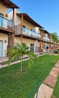 Edifício residencial com várias varandas, gramado bem cuidado e céu limpo.