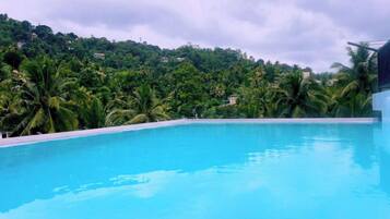 Una piscina azul cristalina con vistas a una verde ladera.