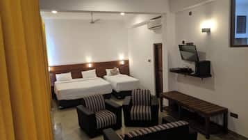 Habitación de hotel con dos camas, televisión, escritorio y zona de estar.