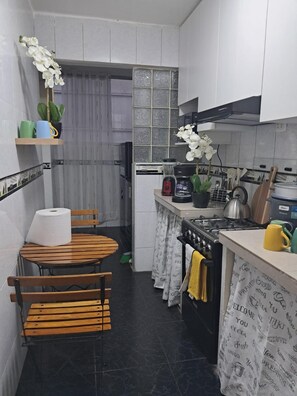 A compact kitchen with a stove, oven, and various utensils. There is a small dining area with a table and chairs. - New Listing (Miraflores)