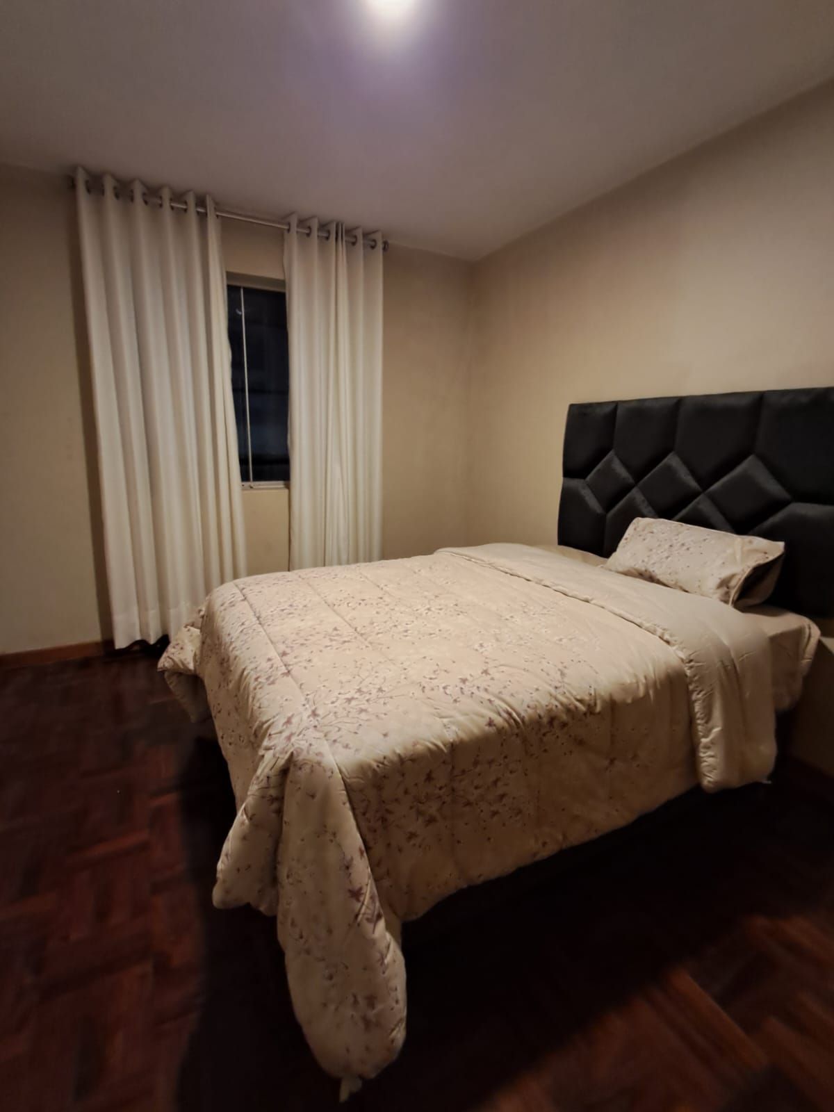 A bedroom with a bed, curtains, and a window.
