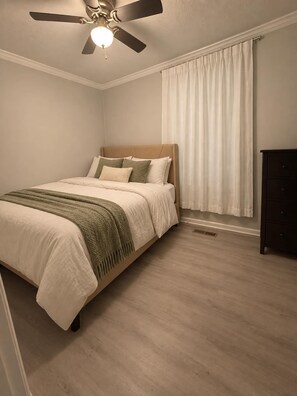 A bedroom with a bed, a ceiling fan, a window with curtains, and a dresser. - Brook Highland House (Birmingham)