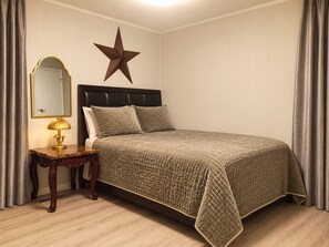 Un dormitori amb un llit, una taula de nit, una làmpada, un mirall i una decoració amb estrelletes a la paret.