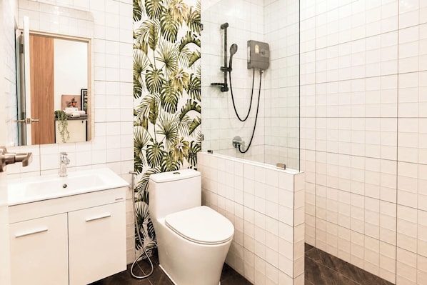 A bathroom with a toilet, sink, and shower area.