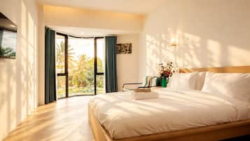 A hotel room with a large bed, a view of palm trees, and a sliding door leading to an outdoor area.