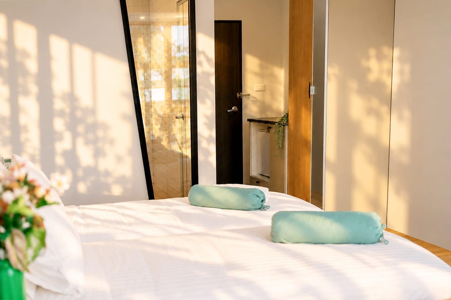 Un dormitorio con cama, dos almohadas, una mesita de noche y un espejo.