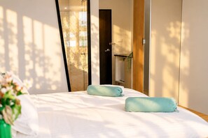 Un dormitorio con cama, dos almohadas, una mesita de noche y un espejo.