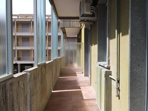 Un passadís estret amb terra de rajola, que condueix a un edifici amb múltiples balcons.