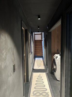 A hallway with a wooden staircase, a washing machine, and a patterned rug. - Tiki Oasis at Indian Circle (Kennesaw)