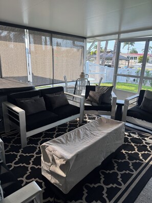 A room with a black and white patterned rug, a white sofa, a white armchair, and a small table with a vase. - Gorgeous 3-bedroom canal waterfront house (New Port Richey)