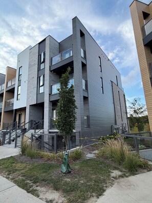 A modern multi-story building with balconies, a staircase, and a small tree in the foreground. - Scenic Kitchener Retreat | Escarpment View Balcony (Kitchener)