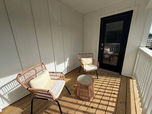 A covered balcony with two wicker chairs and a small round table. - Brand-New home 5 Min to downtown, near beaches, community pool (Port St. Joe)