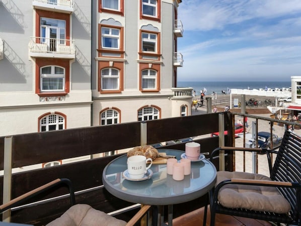 Ein Balkon mit Tisch, Stühlen und Meerblick.