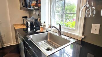 A kitchen with a stainless steel sink, a microwave, and a window with a view of greenery.
