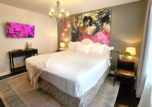 Ein Schlafzimmer mit einem großen Bett, einem Fernseher an der Wand, einer Chandelüster und einem Gemälde.