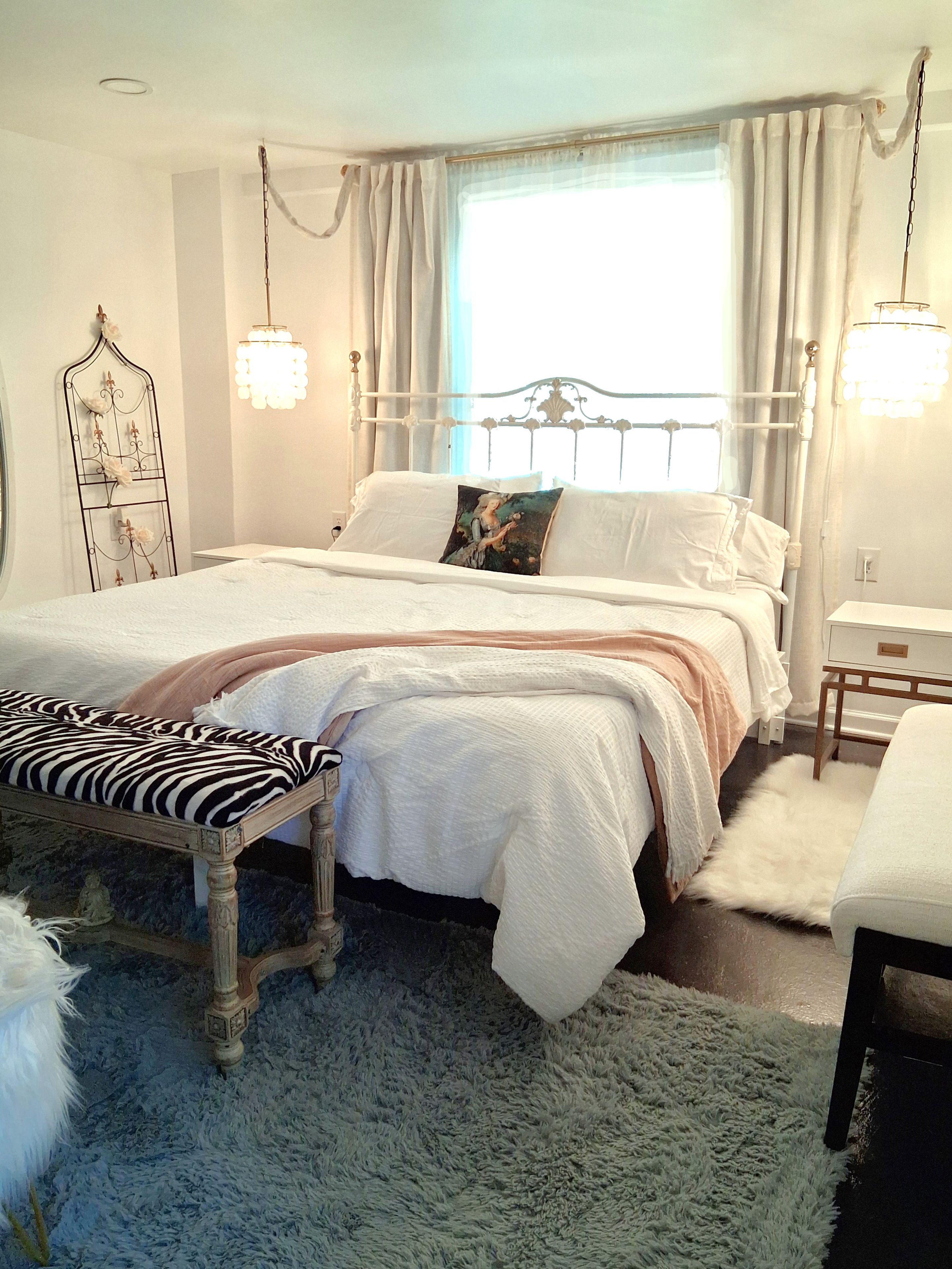 A bedroom with a bed, bedside table, bench, and a decorative headboard.
