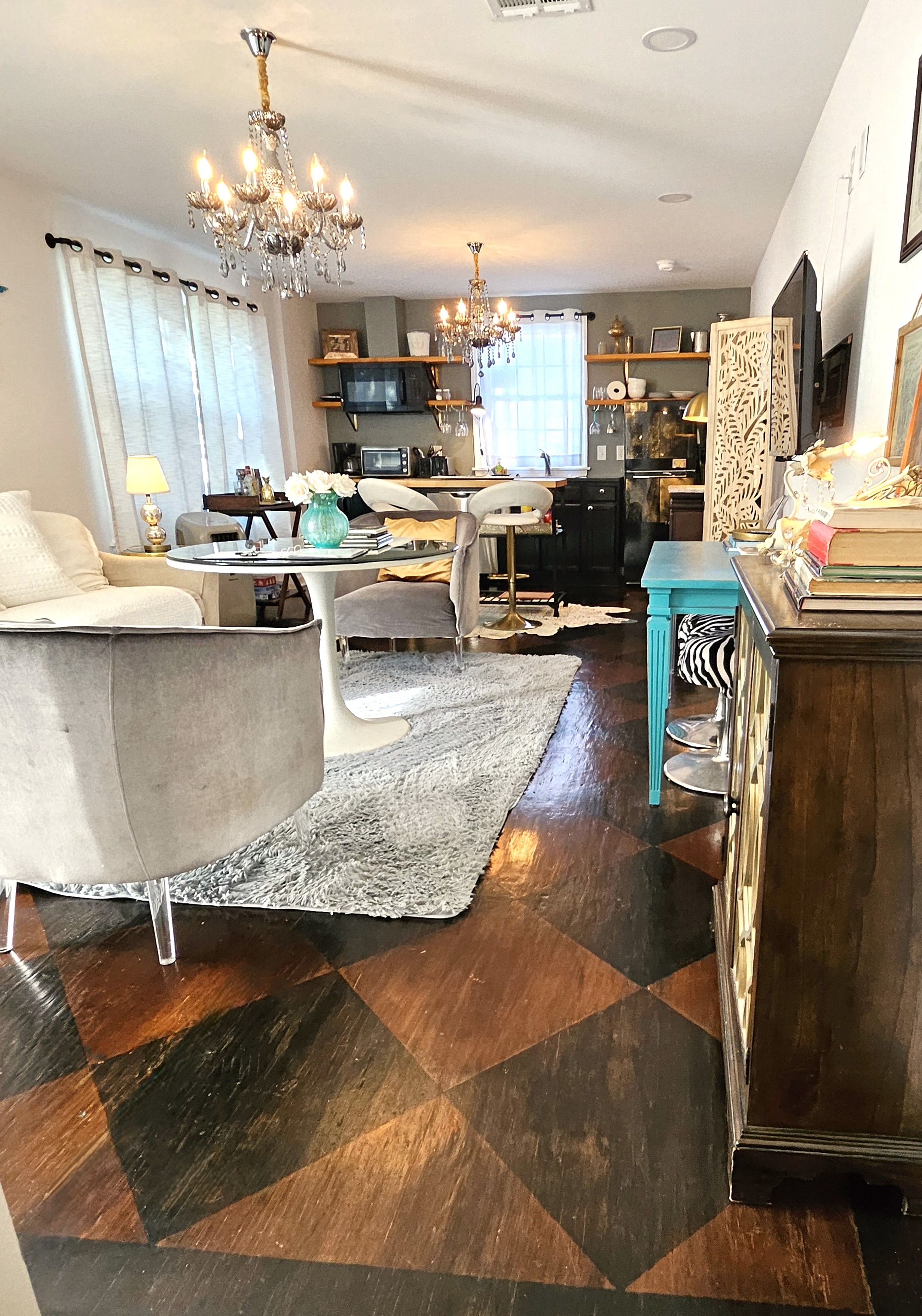 A living room with a sofa, a coffee table, a chandelier, and a patterned rug.