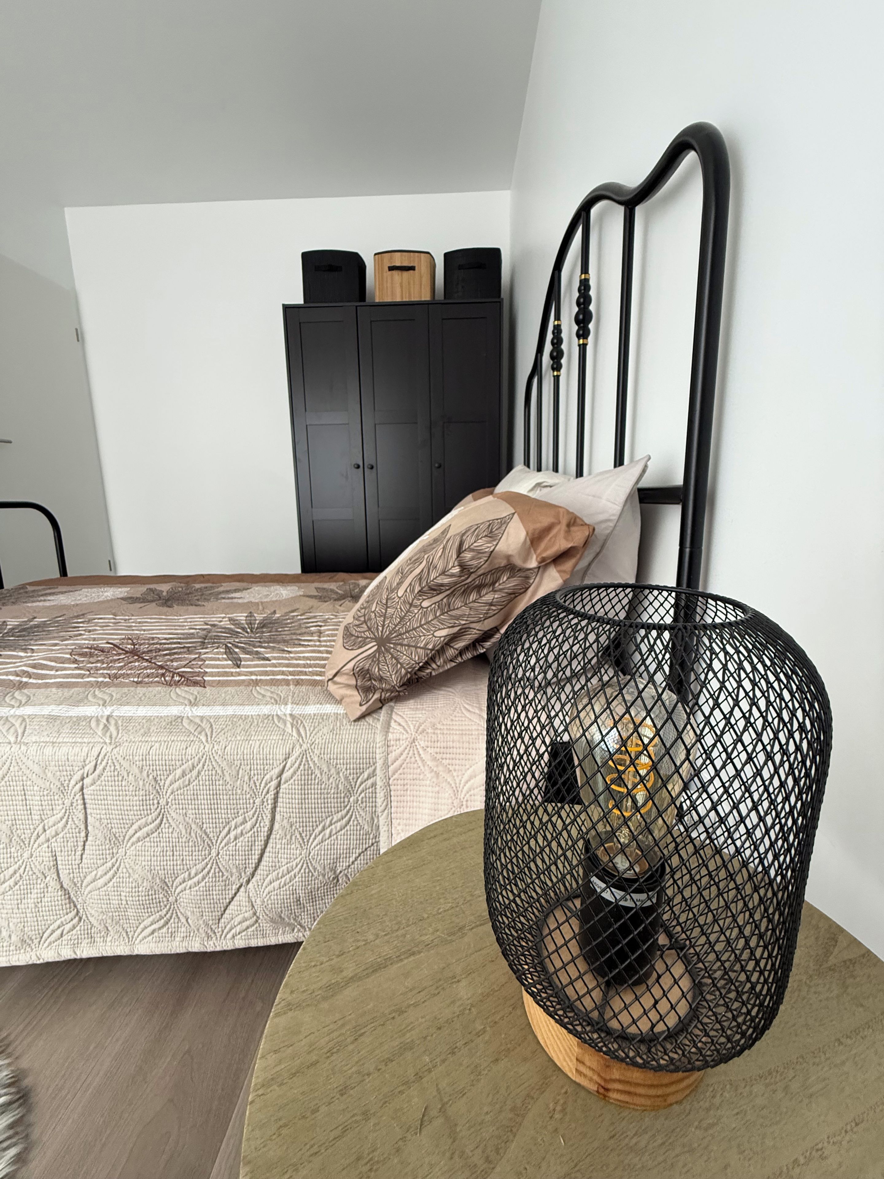 A bedroom with a bed, a wardrobe, and a round table with a decorative item.