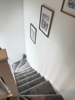 A staircase with carpeted steps leading to a landing. There are framed pictures on the wall above the staircase. - Luxury 5 Bedrooms With 5 Bathrooms (Birmingham)