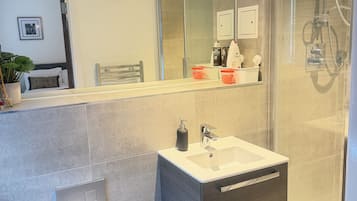 Um banheiro moderno com box de vidro, pia branca e vaso sanitário.