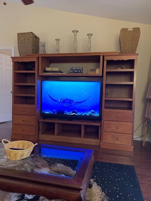 A living room with a wooden entertainment center, a television, and a fish tank. - Beautiful 3/2 House & 2-car Garage (West Melbourne)