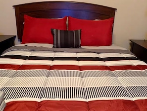 A bed with a striped bedspread, two red pillows, and a single striped pillow. - Beautiful 3/2 House & 2-car Garage (West Melbourne)