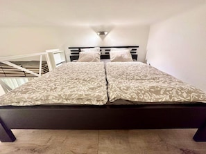 Een bed met hoofdbord, twee kussens en een nachtkastje.