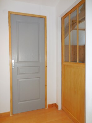 Una porta grisa tancada, amb un marc de fusta i un petit finestral a la part superior.