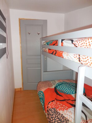 Un llit superposat amb roba de llit estampada, una porta i un objecte fixat a la paret.