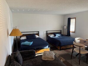 A room with two beds, a desk, a chair, and a lamp. - Cozy ski-in-ski out studio at the base of Schuss Mountain (Mancelona)