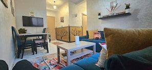 A living room with a sofa, a coffee table, a TV, and a decorative partition. - New Listing (Arrahma)