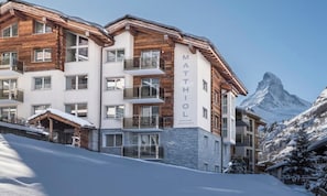 A multi-story hotel with a wooden facade and a mountain view. - EXPERIENCE ALPINE LUXURY IN A SPACIOUS PENTHOUSE OVERLOOKING THE MATTERHORN (Zermatt)