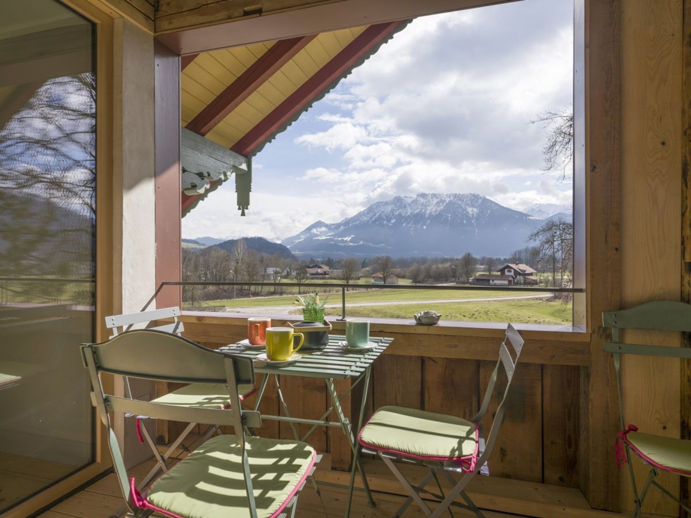 Un terrazzo in legno con tavolo e sedie, con vista su un paesaggio montuoso.