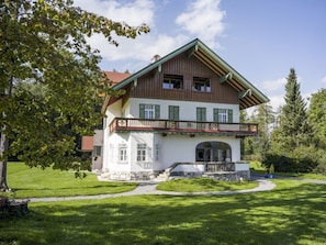 A two-story house with a balcony, a stone base, and a red-tiled roof. - Holiday Apartment With 1 Bedroom (Oberaudorf)